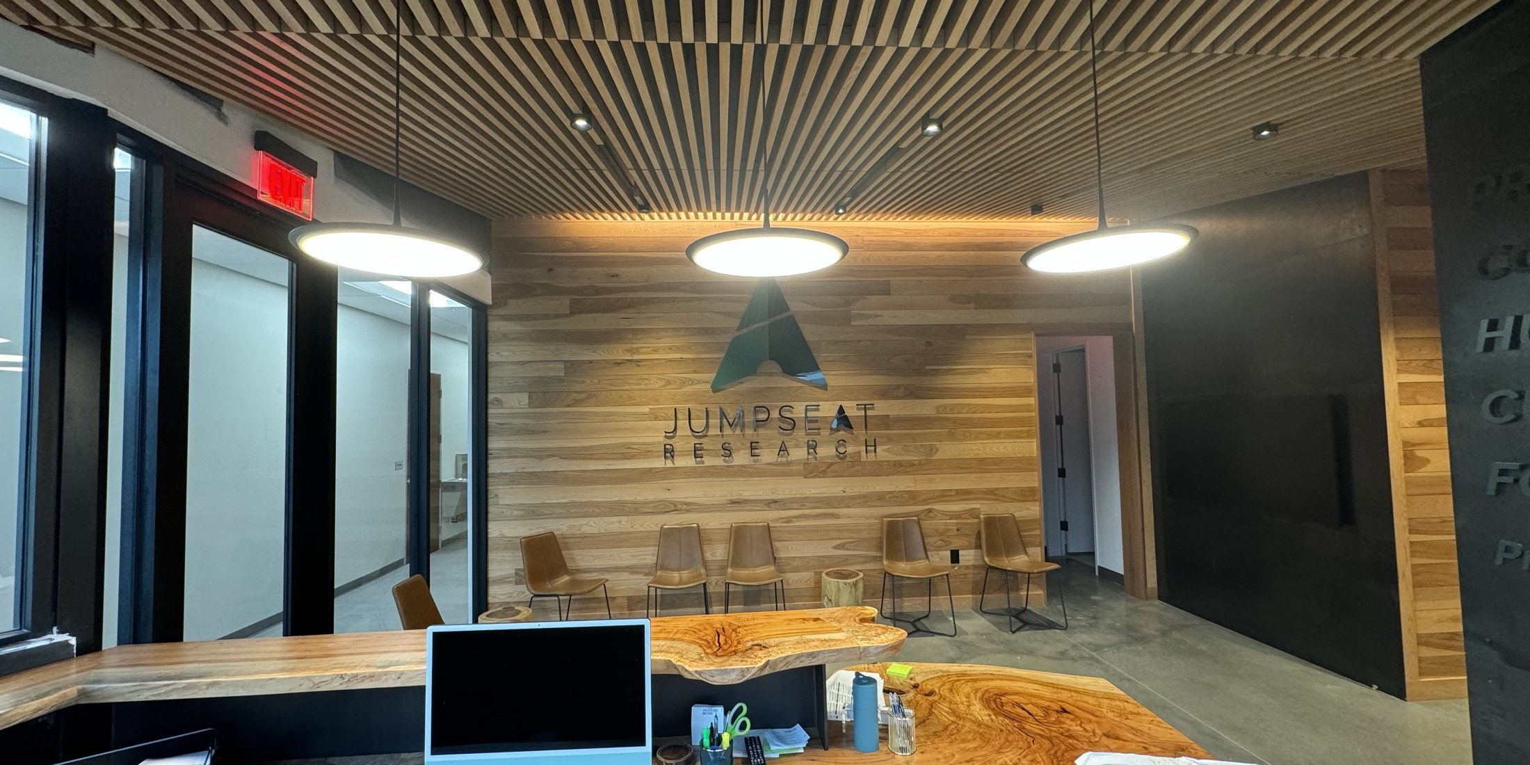 Finished commercial office interior with wood-slat ceiling and pendant lighting